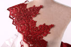 A close-up view of a red lace fabric on a mannequin, showcasing intricate floral and lace patterns.