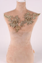 A mannequin with a beige body and gold floral embellishments on the shoulders.