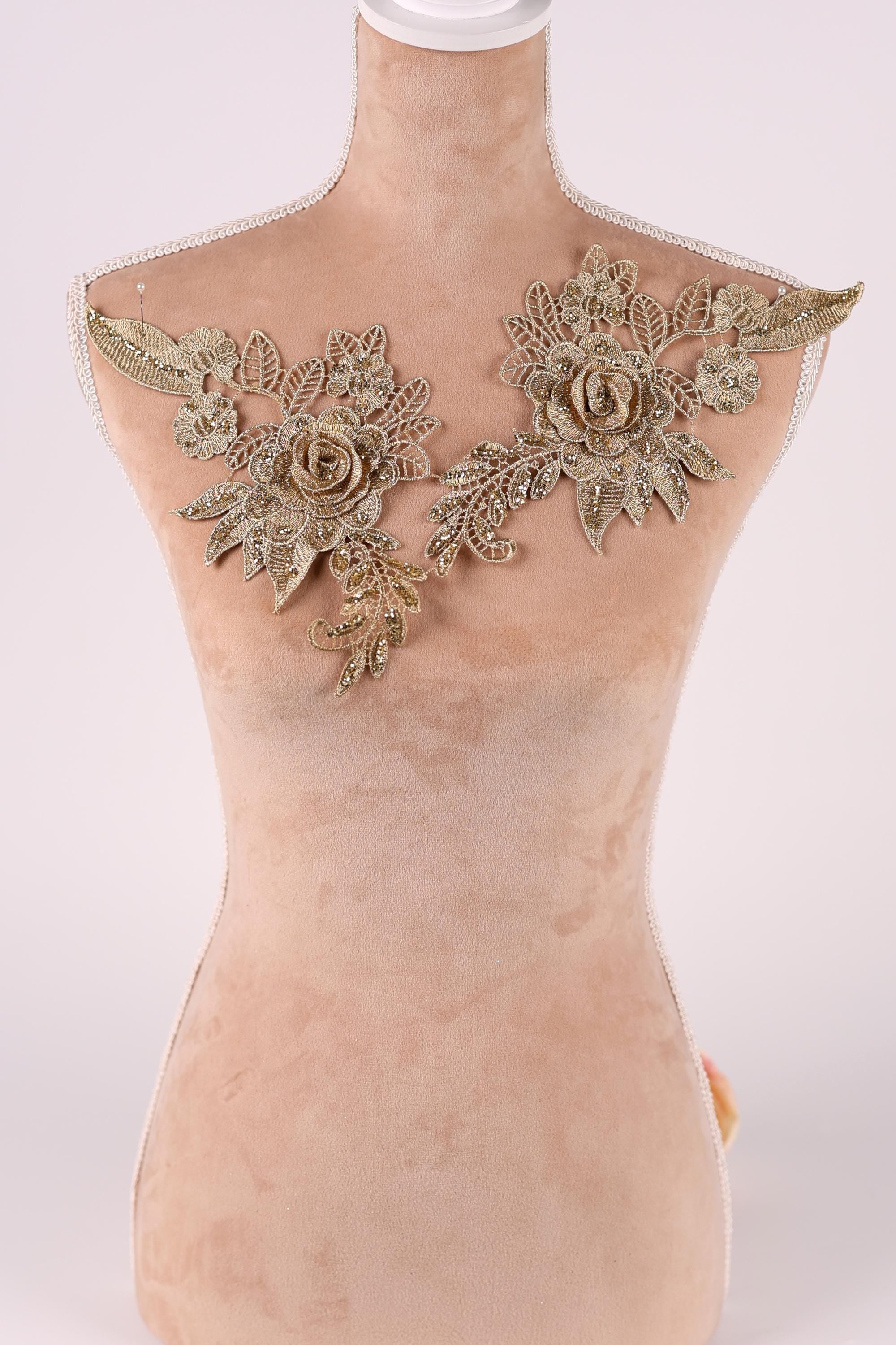 A mannequin with a beige body and gold floral embellishments on the shoulders.