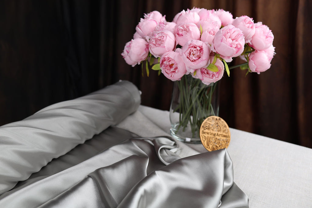 a vase filled with pink flowers on top of a bed
