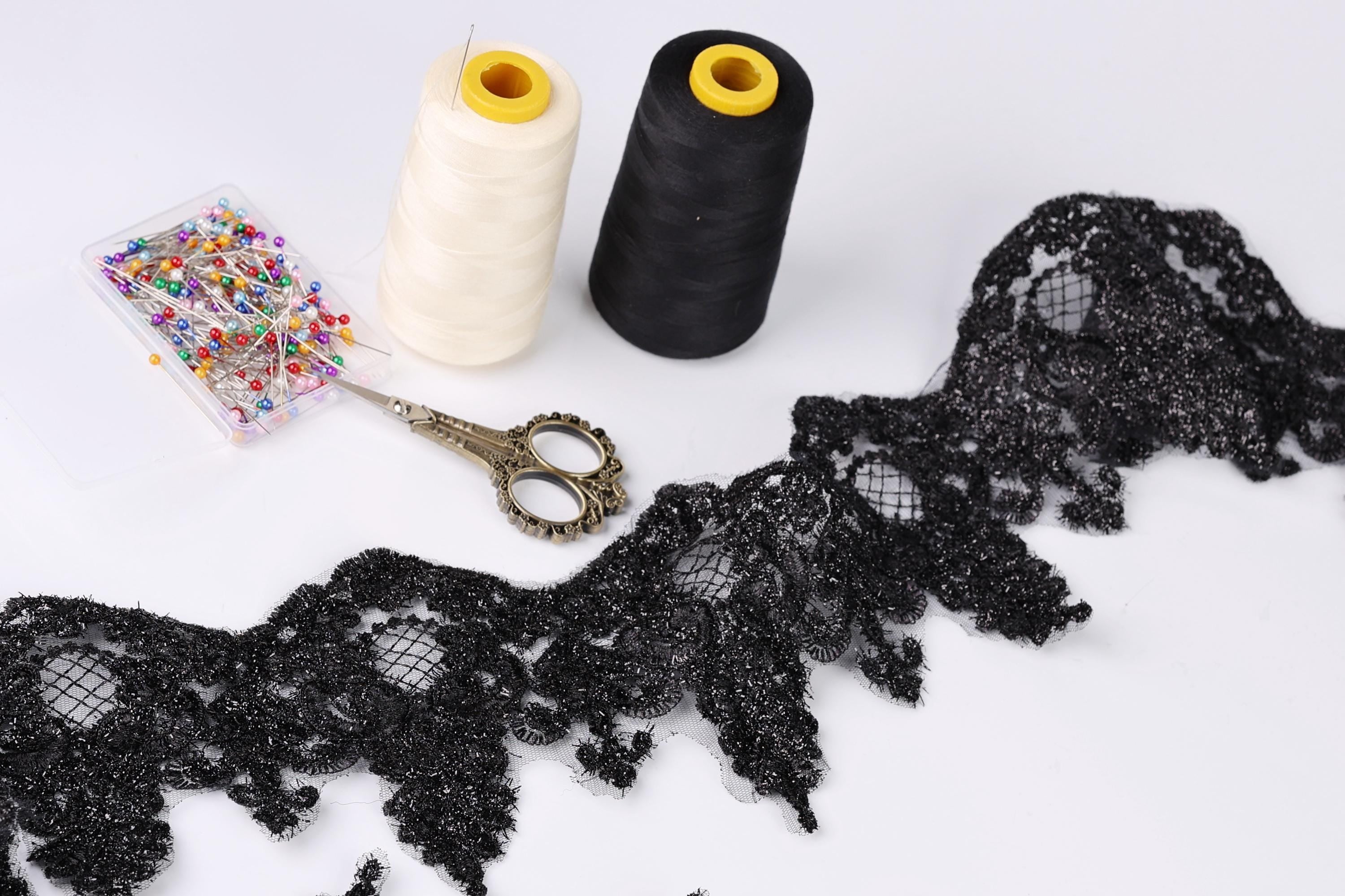 sewing supplies, including two spools of thread, a pair of scissors, and a spool of thread with a yellow tip, arranged on a white background.