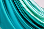 a close-up view of a fabric with a gradient of turquoise and mint colors, creating a visually appealing and vibrant pattern.