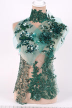 A mannequin wearing a dress with a green floral and sequin pattern.
