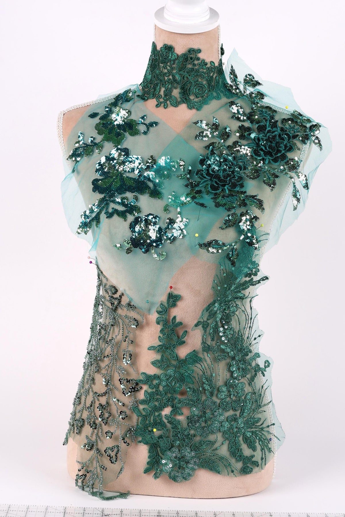 A mannequin wearing a dress with a green floral and sequin pattern.