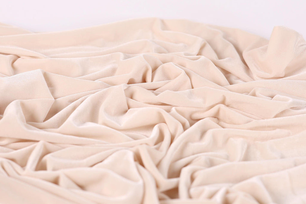 a close-up view of a crumpled, light pink fabric, possibly velvet, with a soft, wrinkled texture.