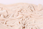 a close-up view of a crumpled, light pink fabric, possibly velvet, with a soft, wrinkled texture.