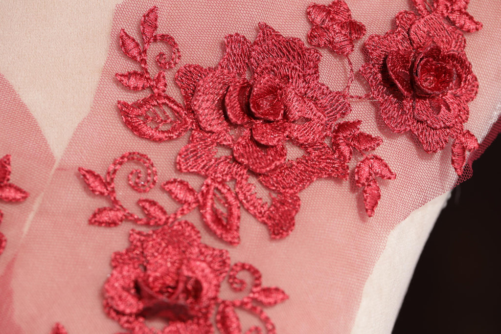 a close-up view of a delicate red floral embroidery on a fabric surface.