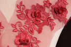 a close-up view of a delicate red floral embroidery on a fabric surface.