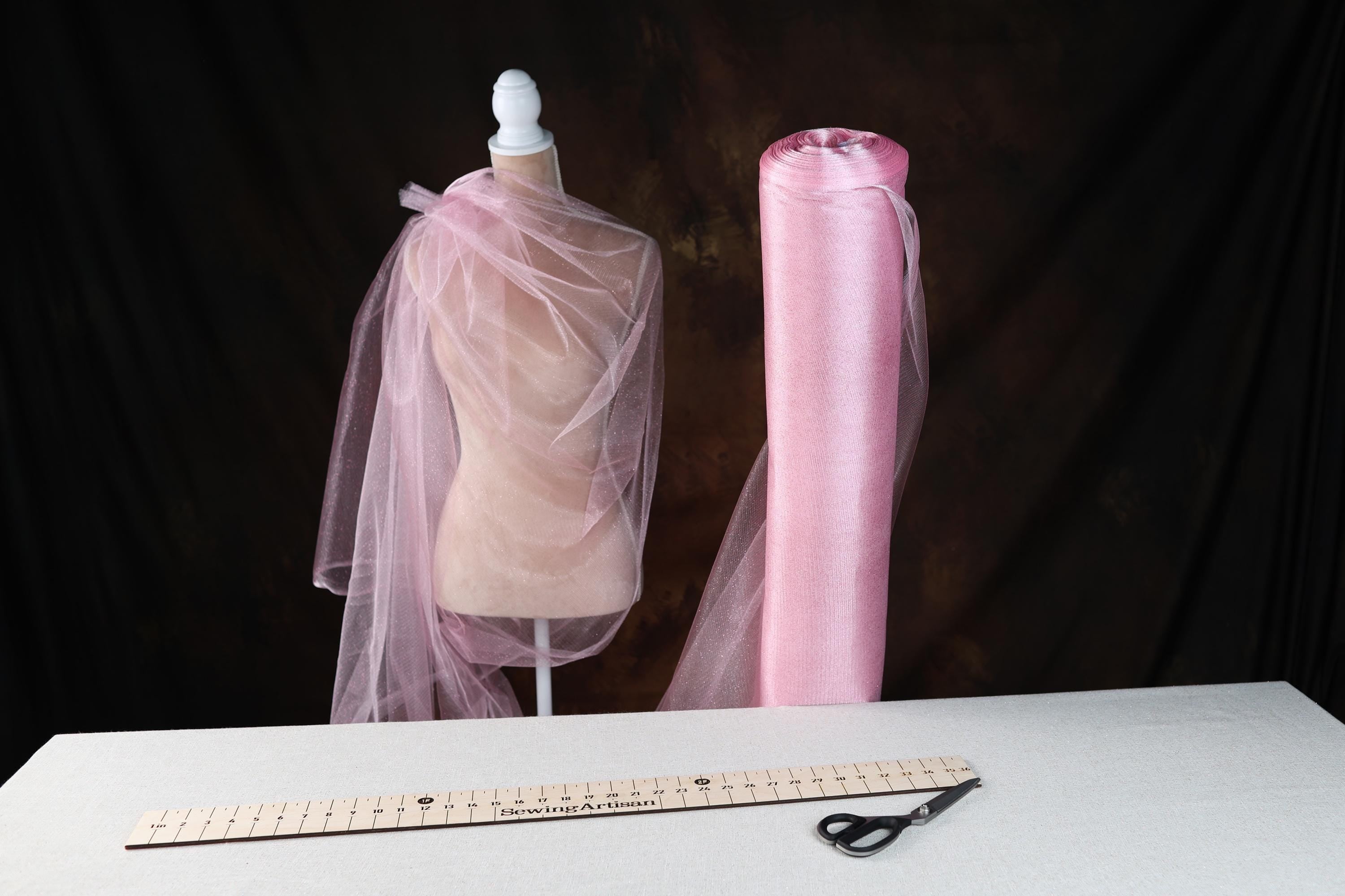 a mannequin with a pink veil and a ruler on a table