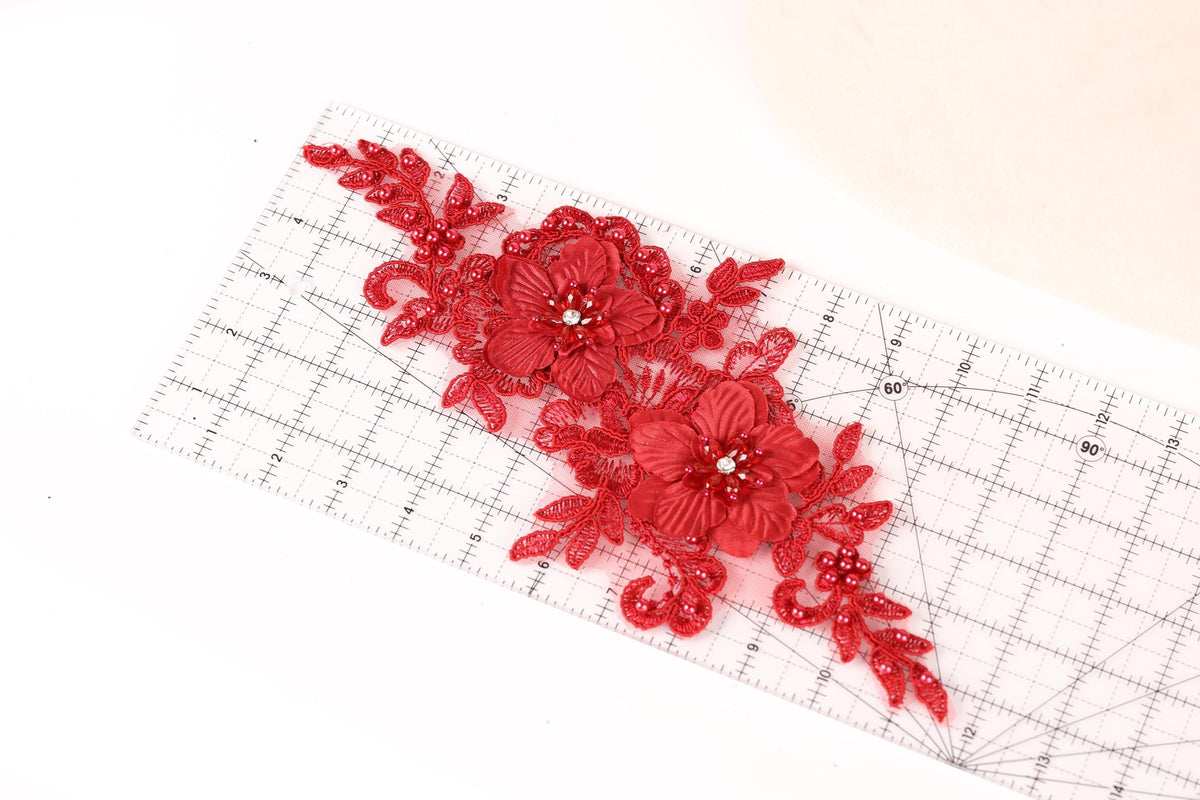 a red floral lace piece with a ruler placed on a white surface.