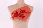 A mannequin with a red fabric piece on its chest, featuring a floral pattern and sequins.