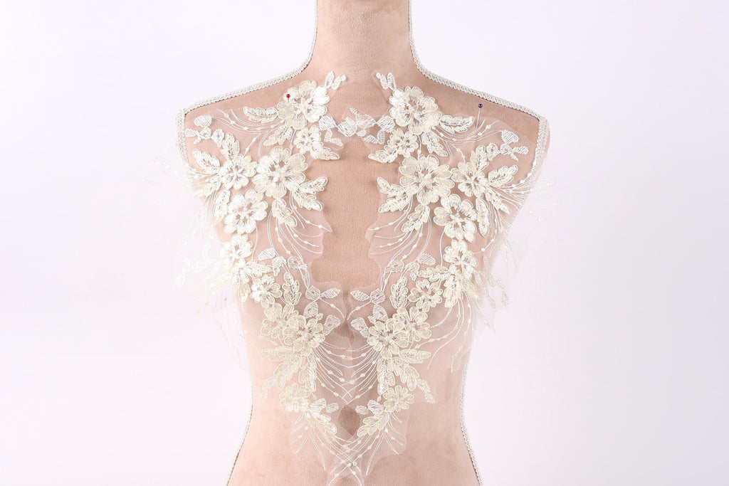 A mannequin wearing a white lace dress with intricate floral embroidery on the back.