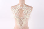 A mannequin wearing a white lace dress with intricate floral embroidery on the back.