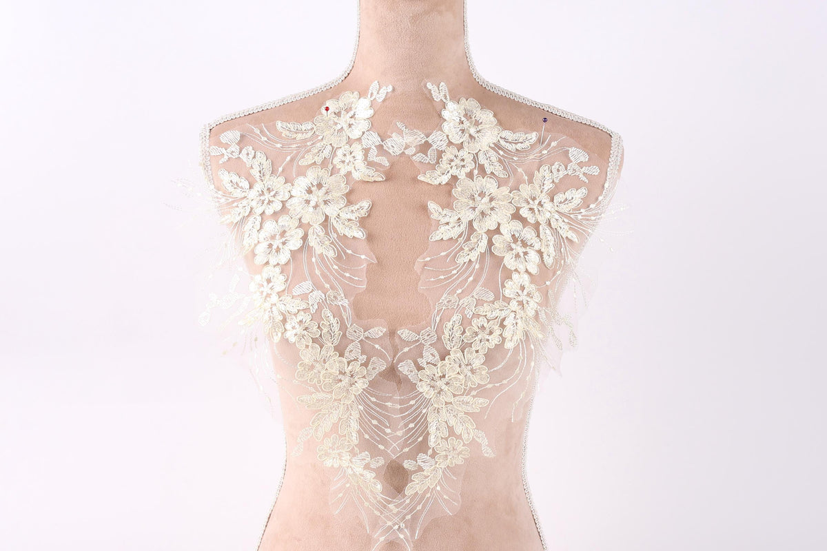 A mannequin wearing a white lace dress with intricate floral embroidery on the back.