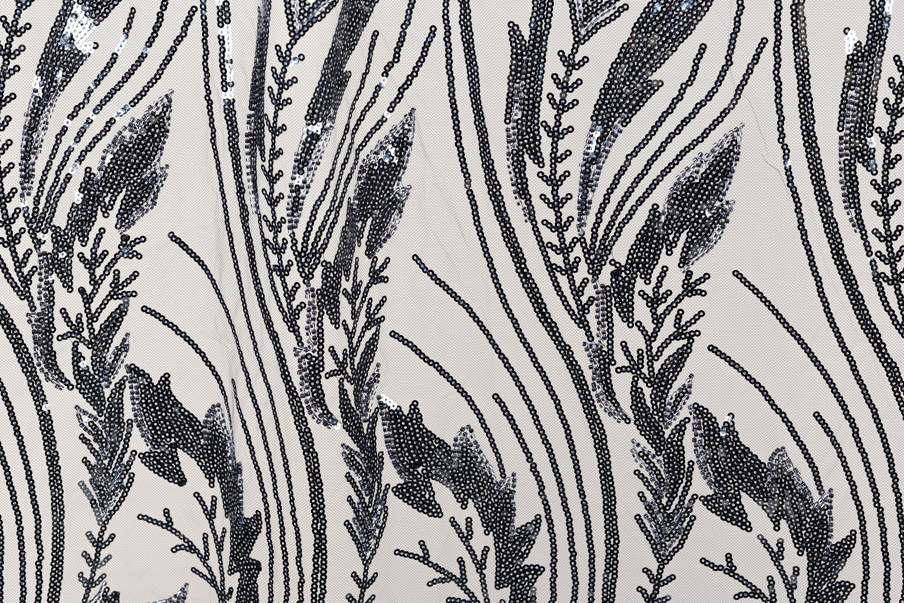 a close-up view of a fabric with a repeating pattern of black and white lines and shapes, resembling a floral or leaf-like design.
