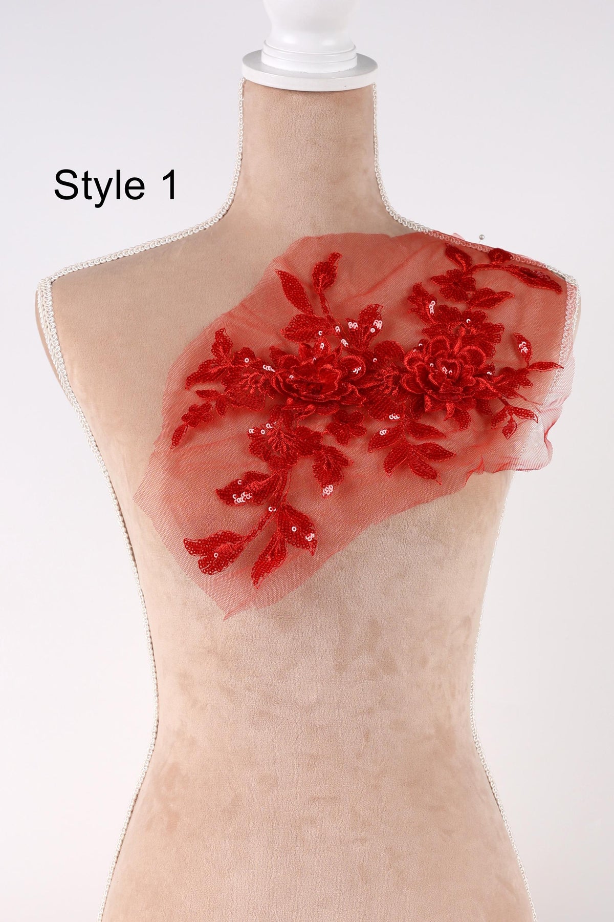 A mannequin with a red floral embellishment on its shoulder.