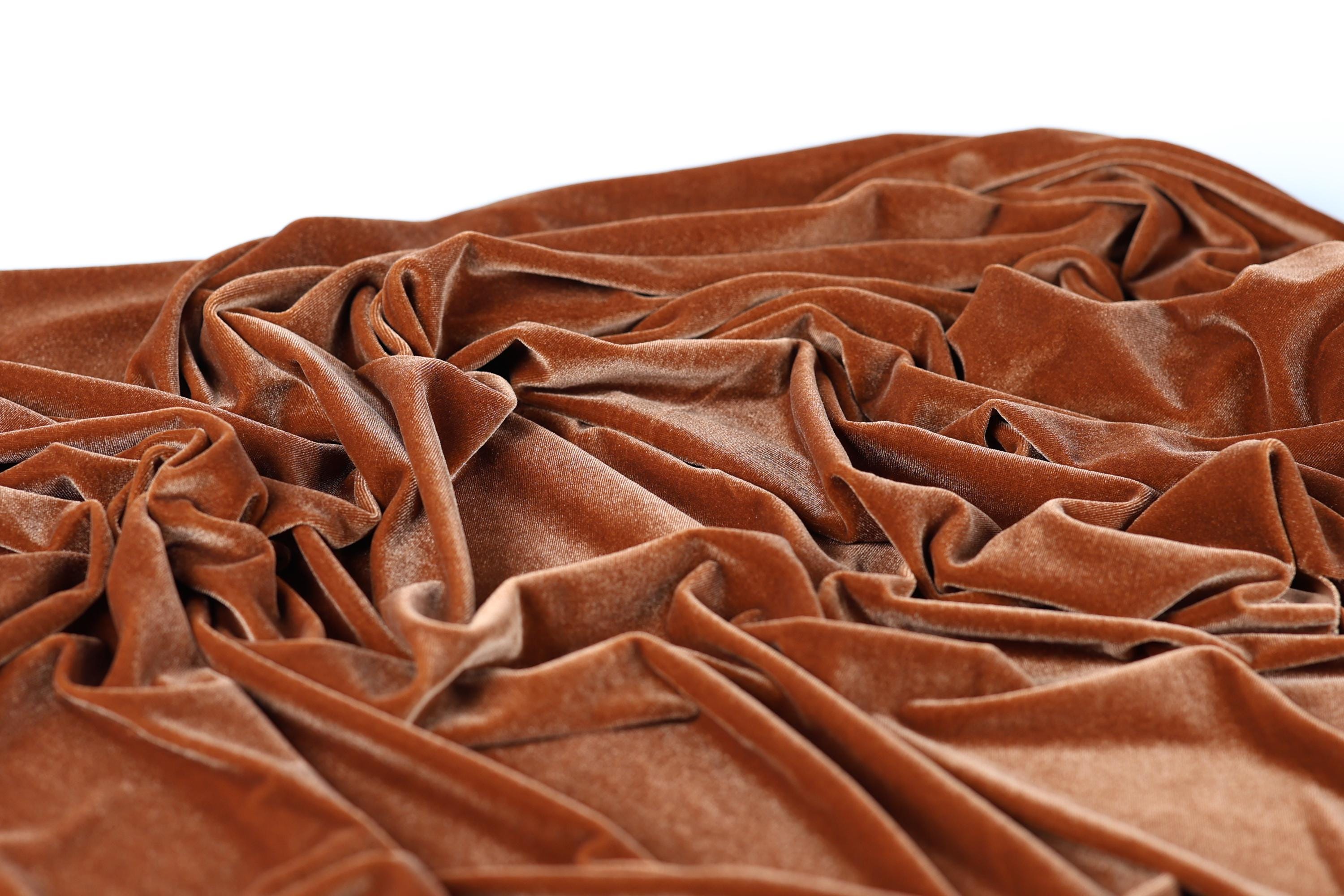 a close-up view of a crumpled, orange-brown fabric, possibly velvet, with a textured and wrinkled appearance.