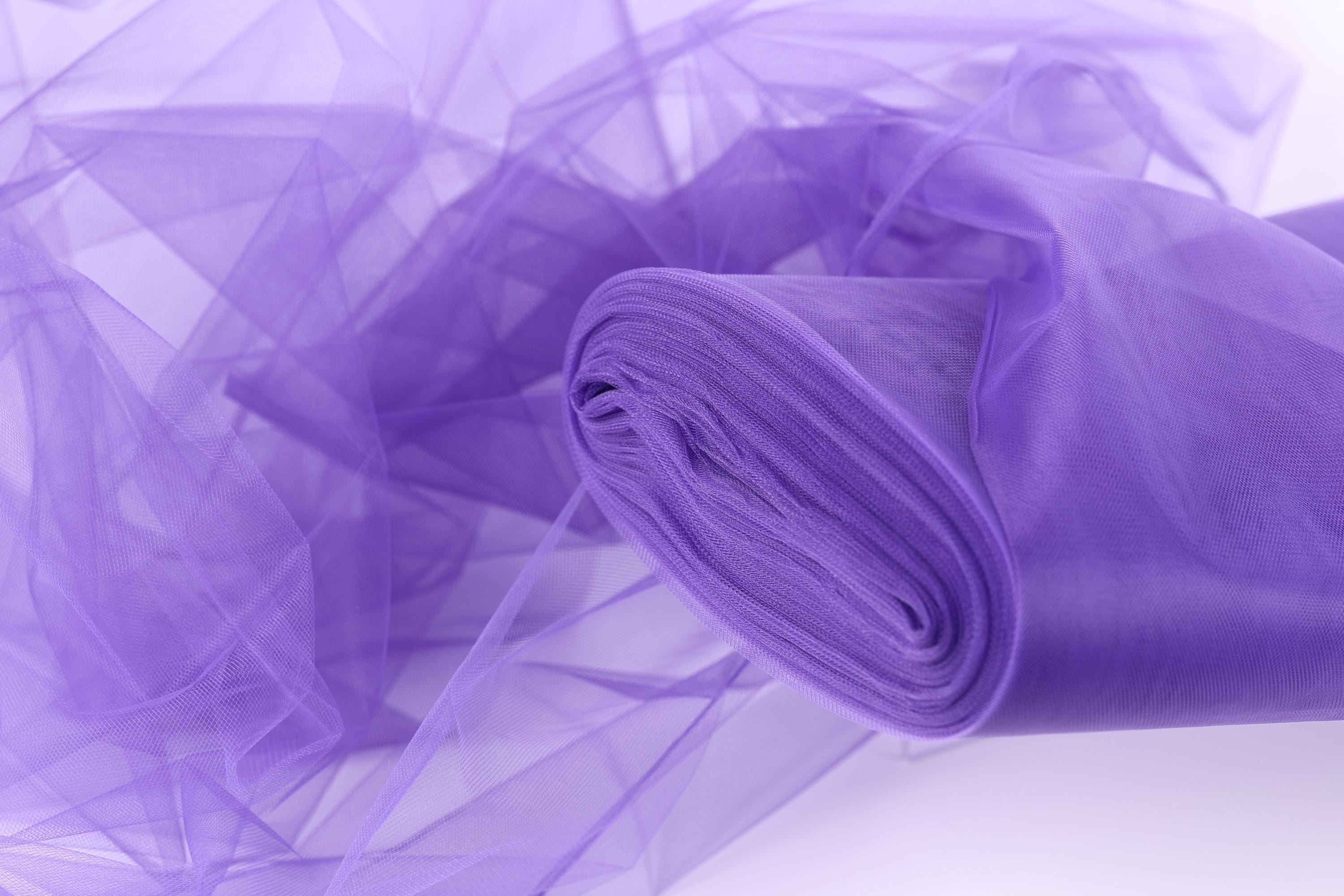 A close-up view of a piece of purple tulle fabric, with its delicate and flowing texture visible.