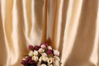 A bouquet of red and white flowers is displayed against a shiny gold fabric background.