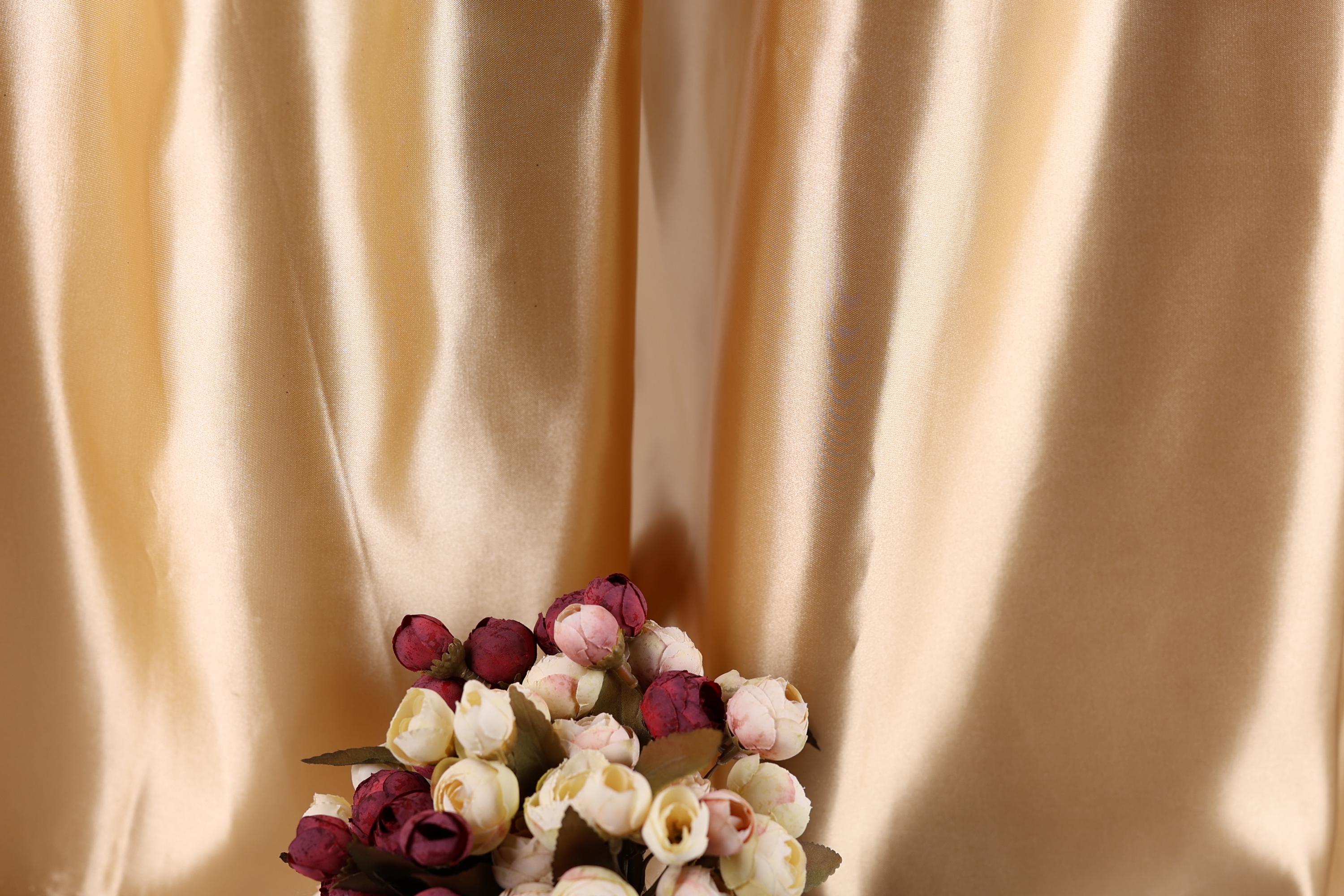 A bouquet of red and white flowers is displayed against a shiny gold fabric background.