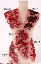 A mannequin with various red floral and lace designs on its body, including a red rose, black lace, and other intricate patterns.