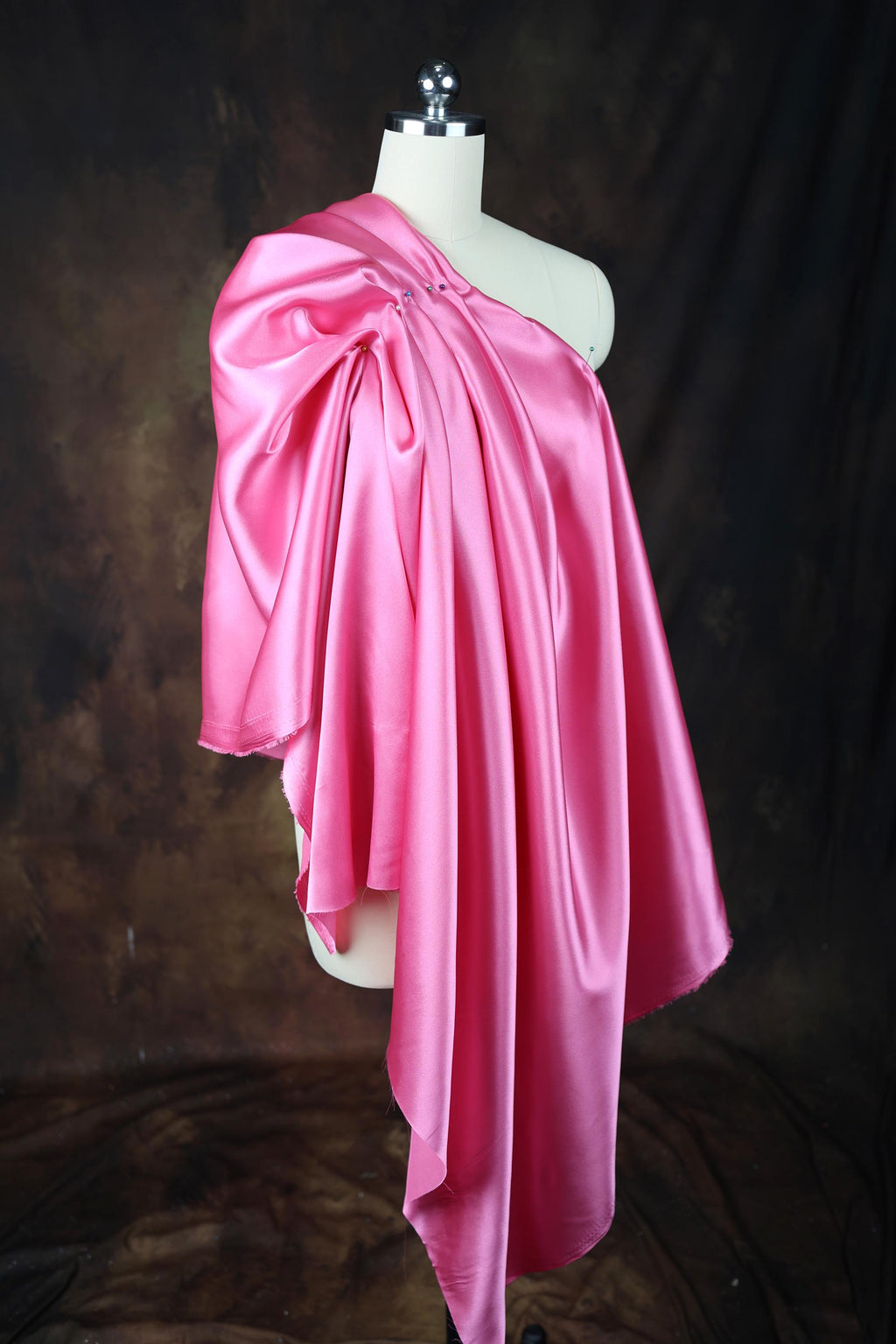 a mannequin wearing a pink scarf on a black background
