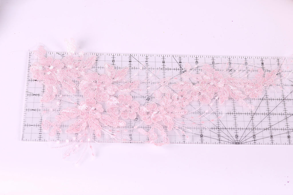 a clear ruler with delicate pink lace flowers placed on it.