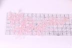a clear ruler with delicate pink lace flowers placed on it.