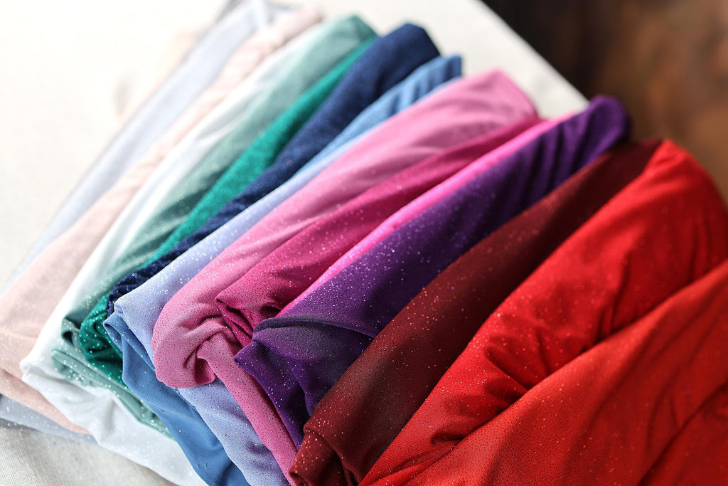 a bunch of different colors of cloth on a bed