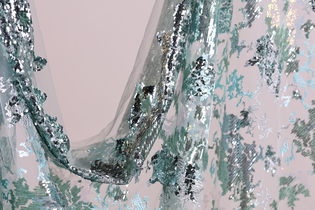 a close-up view of a fabric with a floral pattern and sequin details, creating a visually appealing and intricate design.