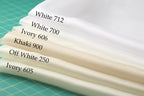 A close-up of a white fabric with the names of different shades of white printed on it, arranged in a descending order from light to dark.