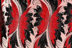 a close-up view of a fabric with a striking pattern of red and black butterflies. The butterflies are intricately designed with black and red sequins, giving the fabric a vibrant and eye-catching appearance. The butterflies are arranged in a repeating pattern, creating a sense of rhythm and movement across the fabric.
