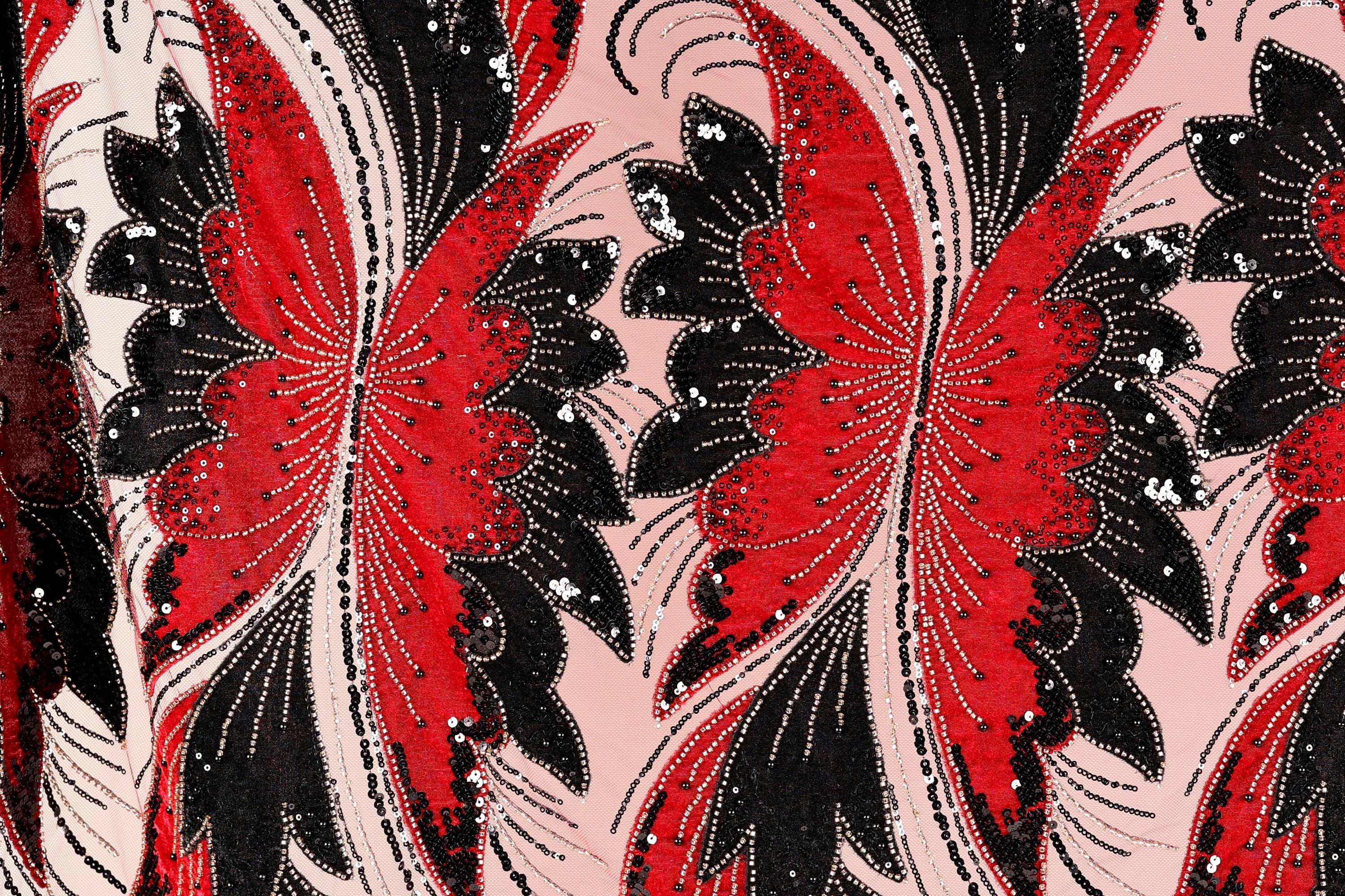 a close-up view of a fabric with a striking pattern of red and black butterflies. The butterflies are intricately designed with black and red sequins, giving the fabric a vibrant and eye-catching appearance. The butterflies are arranged in a repeating pattern, creating a sense of rhythm and movement across the fabric.