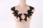 A mannequin wearing a black lace dress with intricate floral patterns.