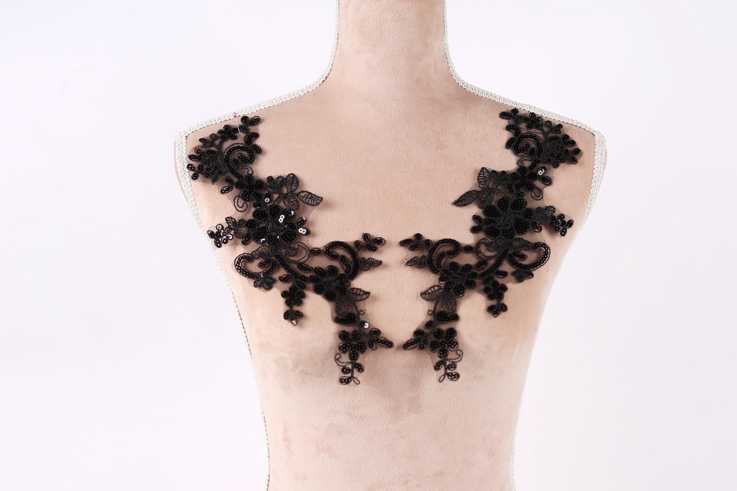 A mannequin wearing a black lace dress with intricate floral patterns.