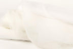 The image is a close-up of a white fabric, possibly a sheer or sheer-like material, with a soft, flowing texture.