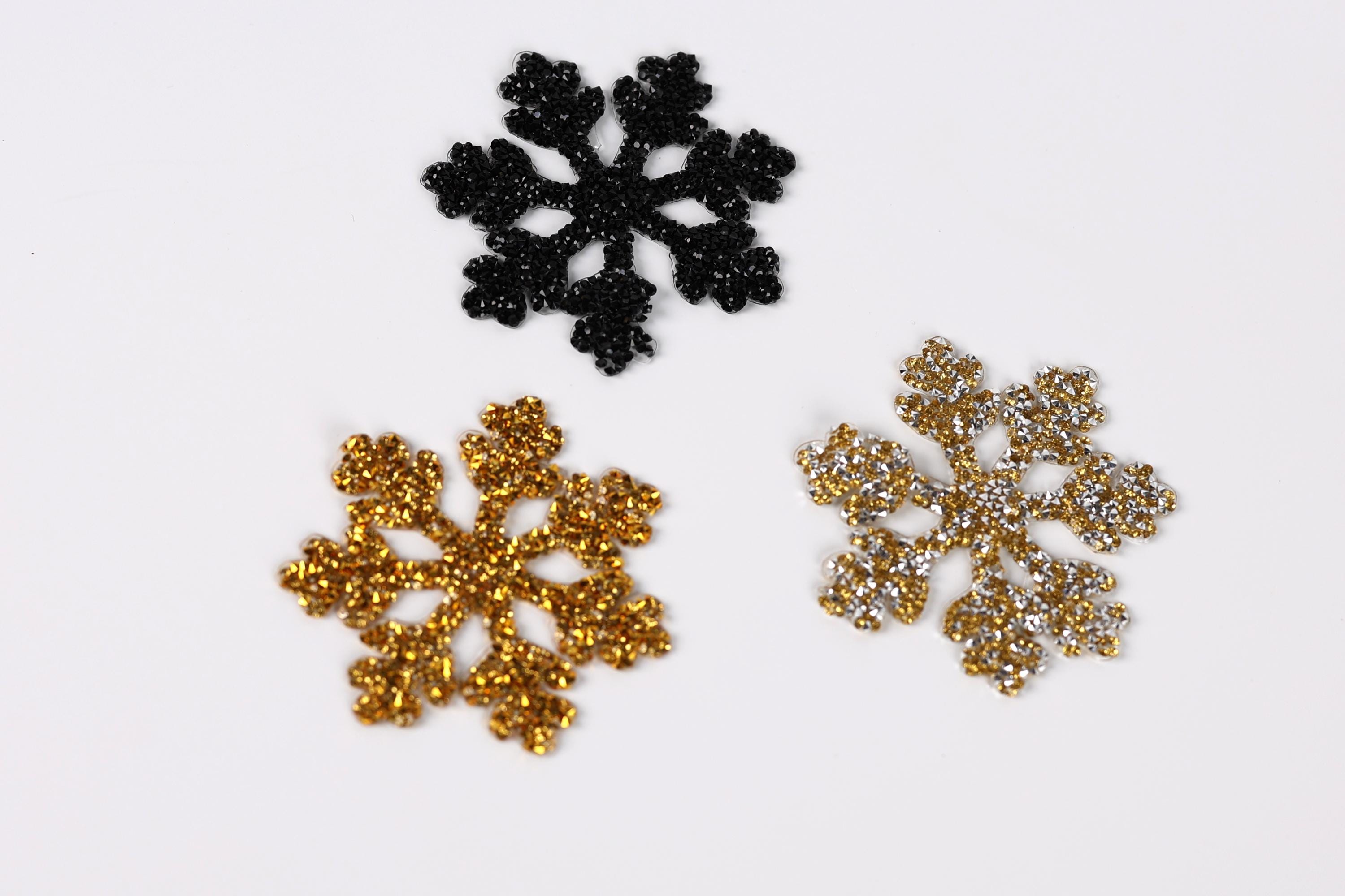 three glittery snowflake decorations of different sizes and colors against a white background.