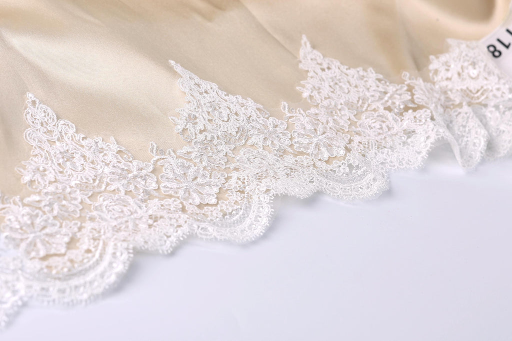 A close-up view of a delicate, white lace trim on a fabric, with intricate patterns and designs.