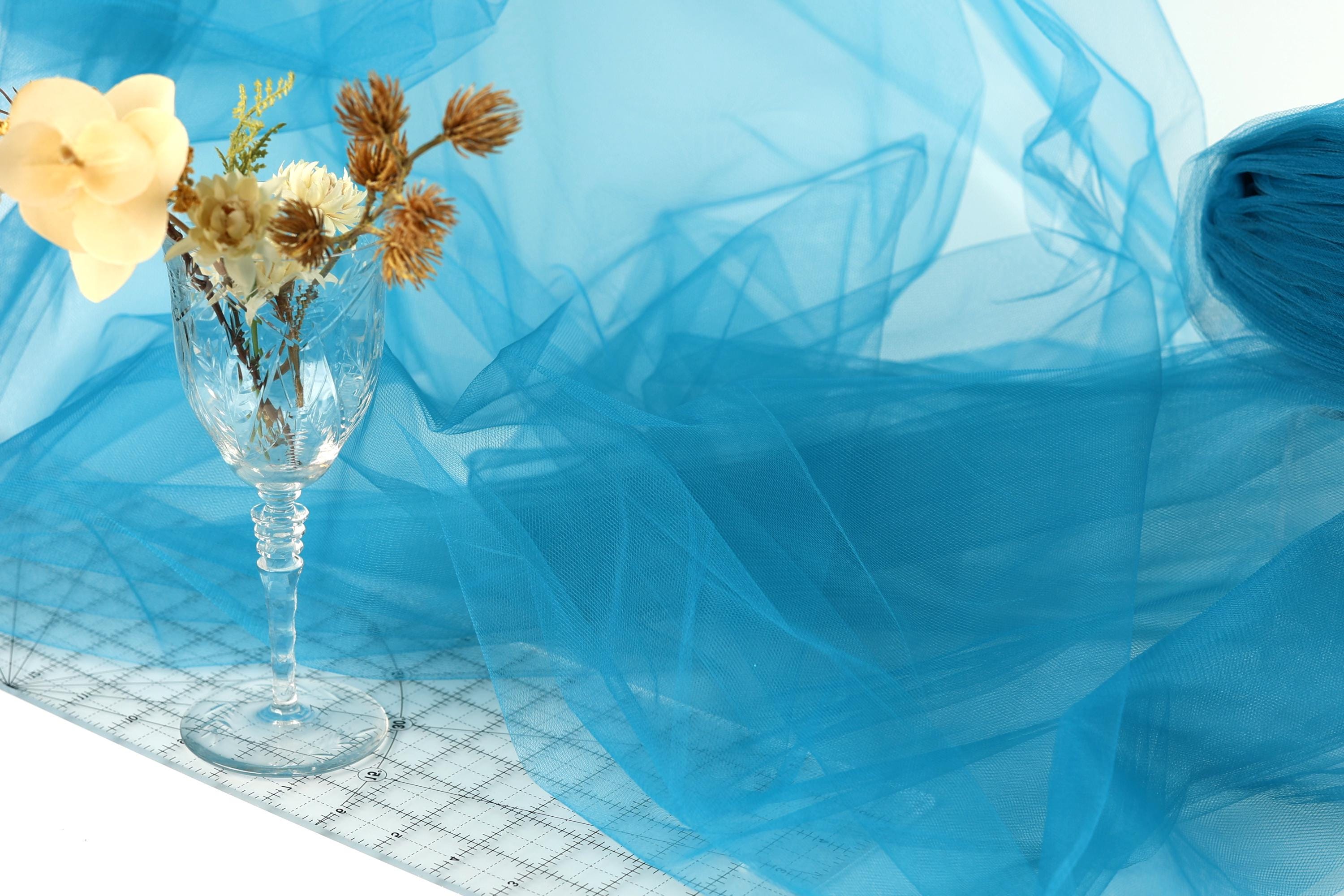 A glass vase filled with flowers sits on a blue fabric surface, creating a visually appealing and harmonious composition.