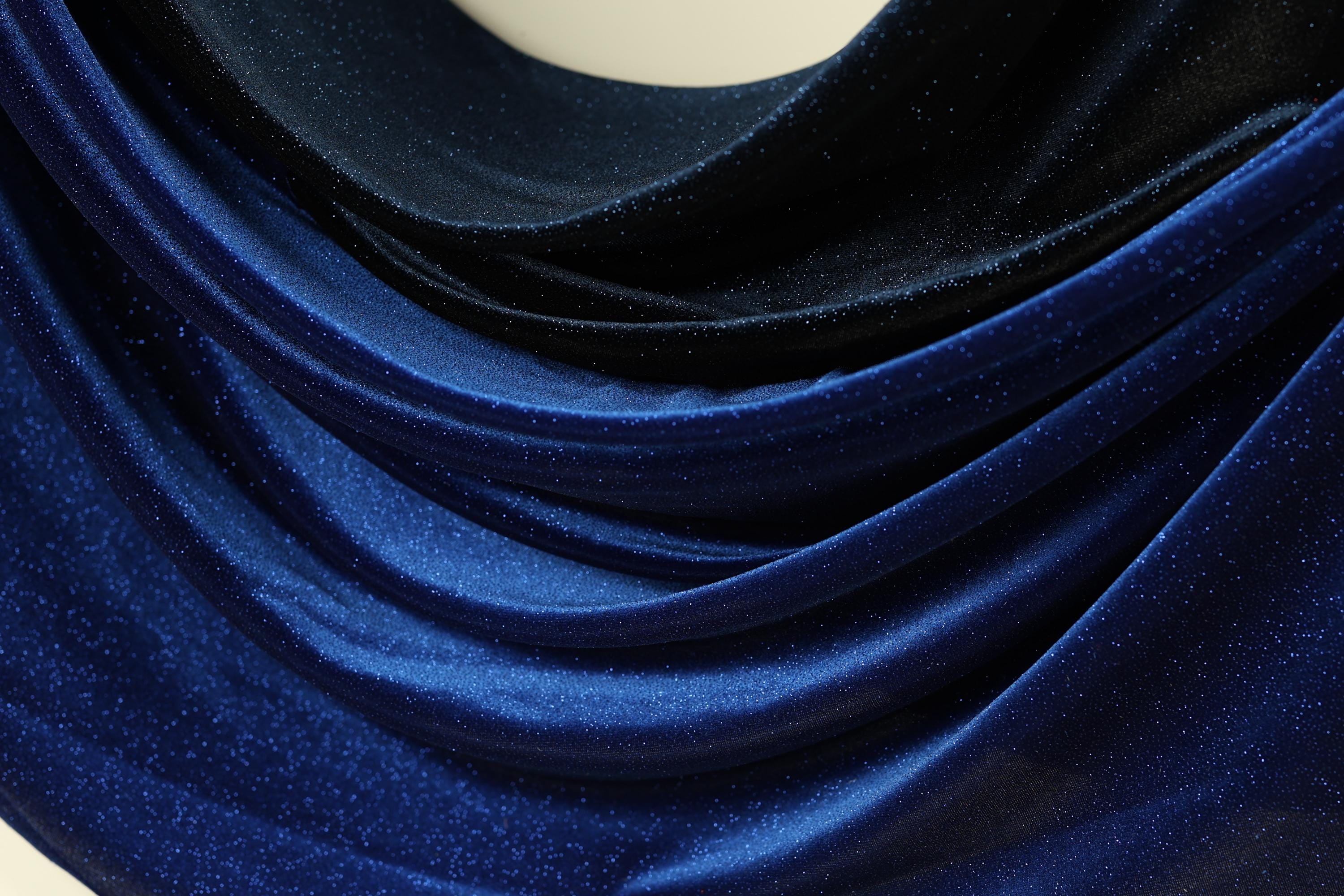 a close-up view of a fabric with a shiny, glittery texture in shades of blue and black.