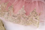 a close-up view of a delicate, pink tulle skirt with intricate gold embroidery and sequins.