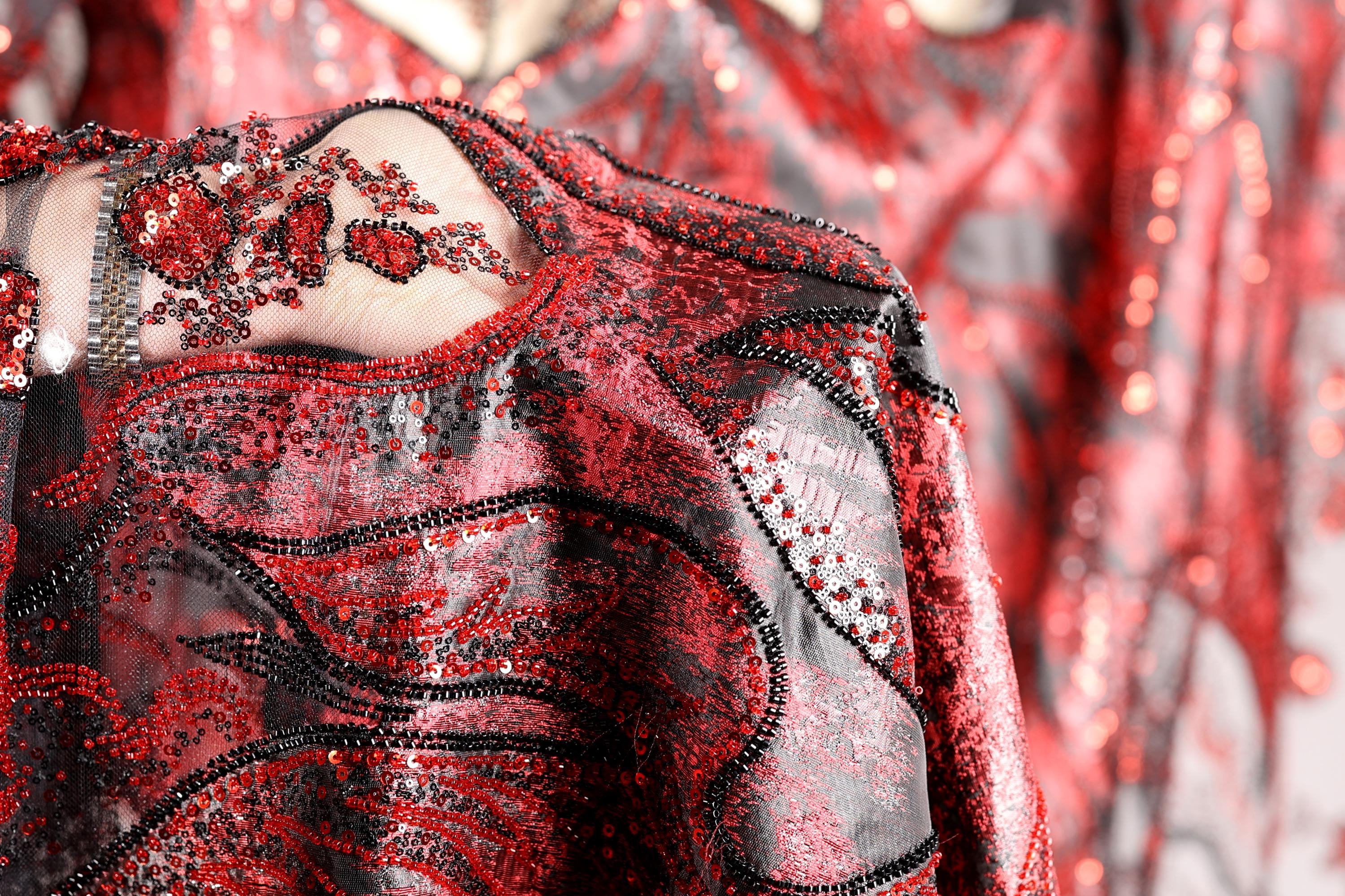a close-up view of a red and black sequined dress with intricate patterns and designs.