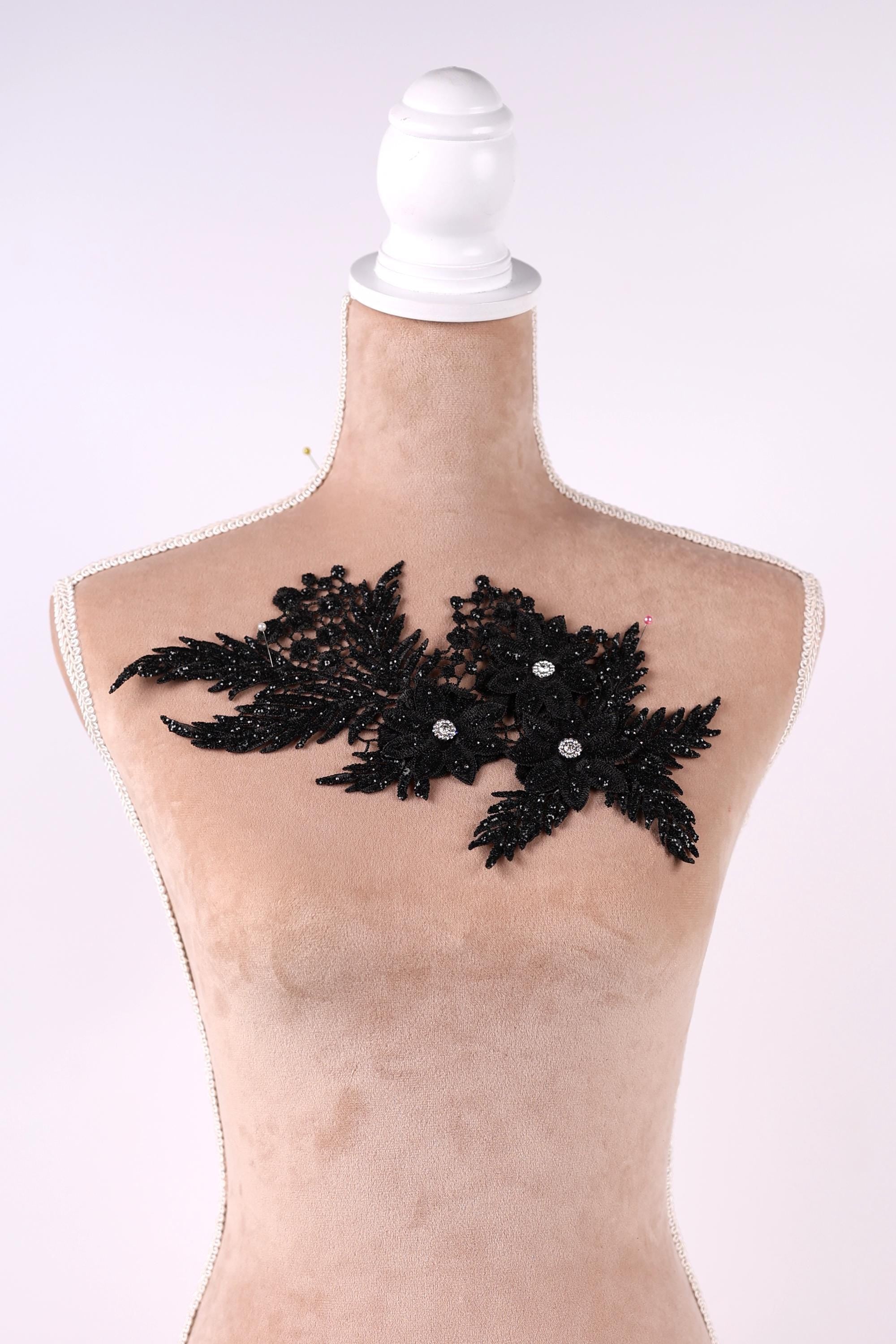 A mannequin with a beige body and a white headpiece, featuring a black lace-like design with small white beads or sequins.
