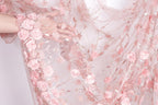 A hand is holding a delicate, pink floral fabric with intricate designs.