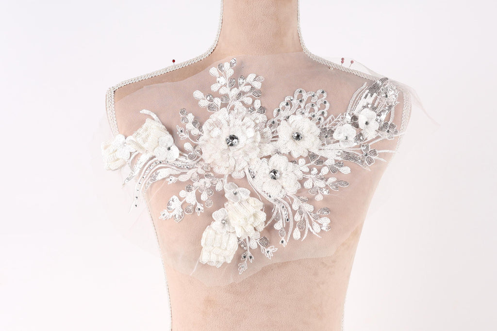A mannequin with a decorative white lace bodice featuring a floral pattern.