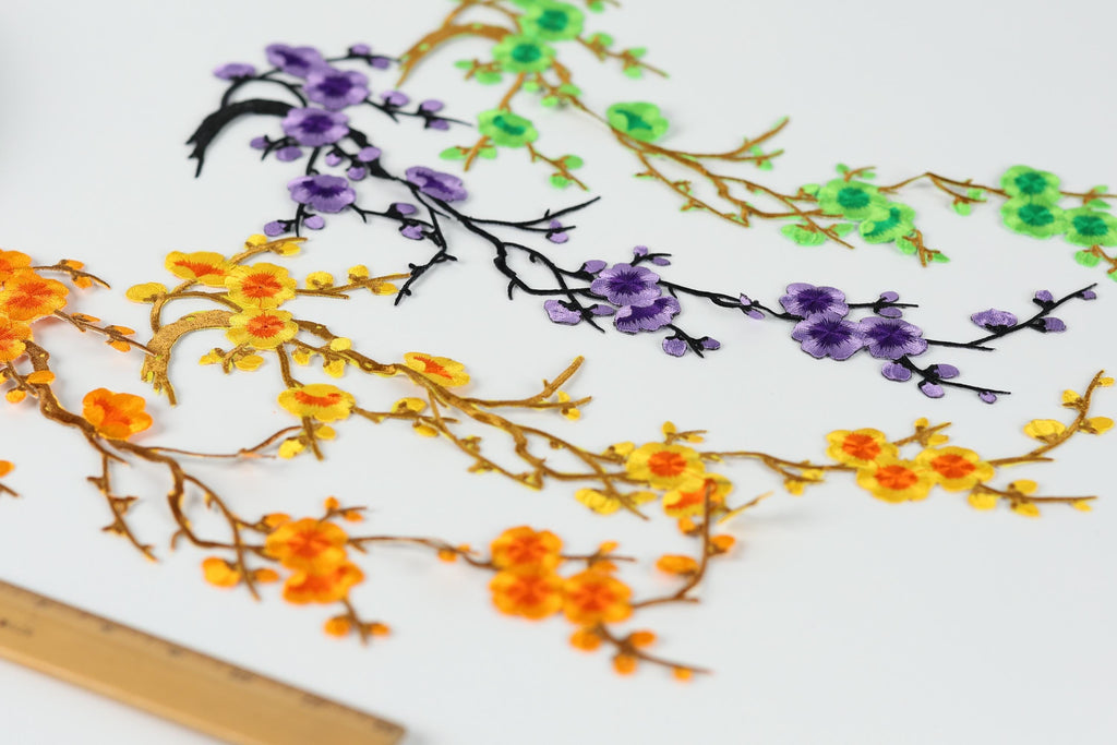 a variety of colorful flowers and branches, including orange, yellow, purple, and green flowers, arranged in a visually appealing manner.