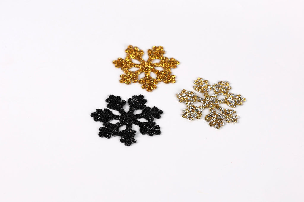 three snowflake-shaped objects, each with a unique color and design, arranged on a white background.
