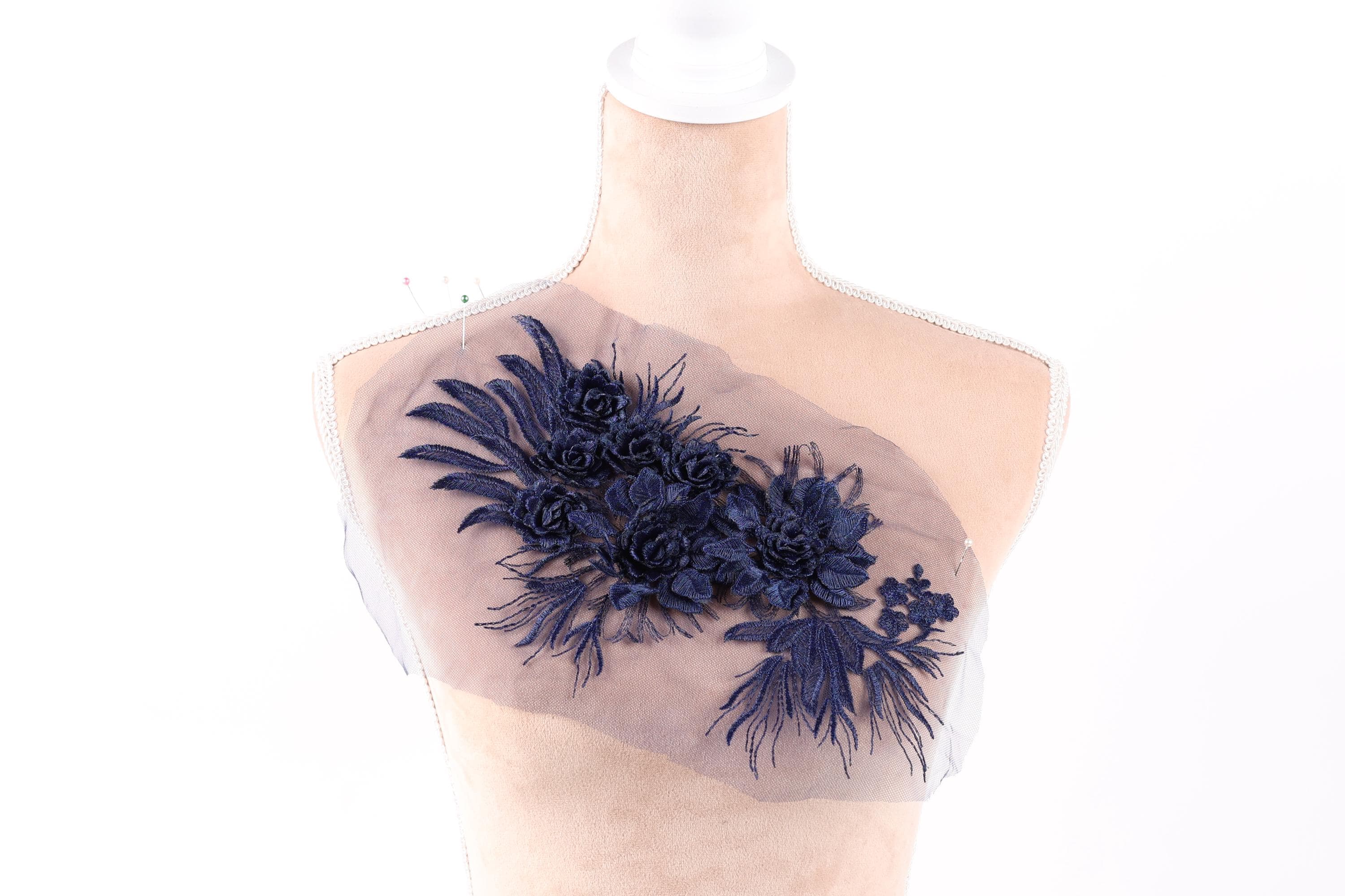A mannequin wearing a dress with a decorative floral embroidered on the bust area.