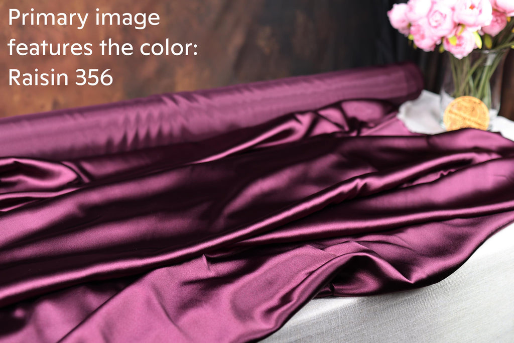 a purple satin fabric, with a vase of pink flowers placed next to it.