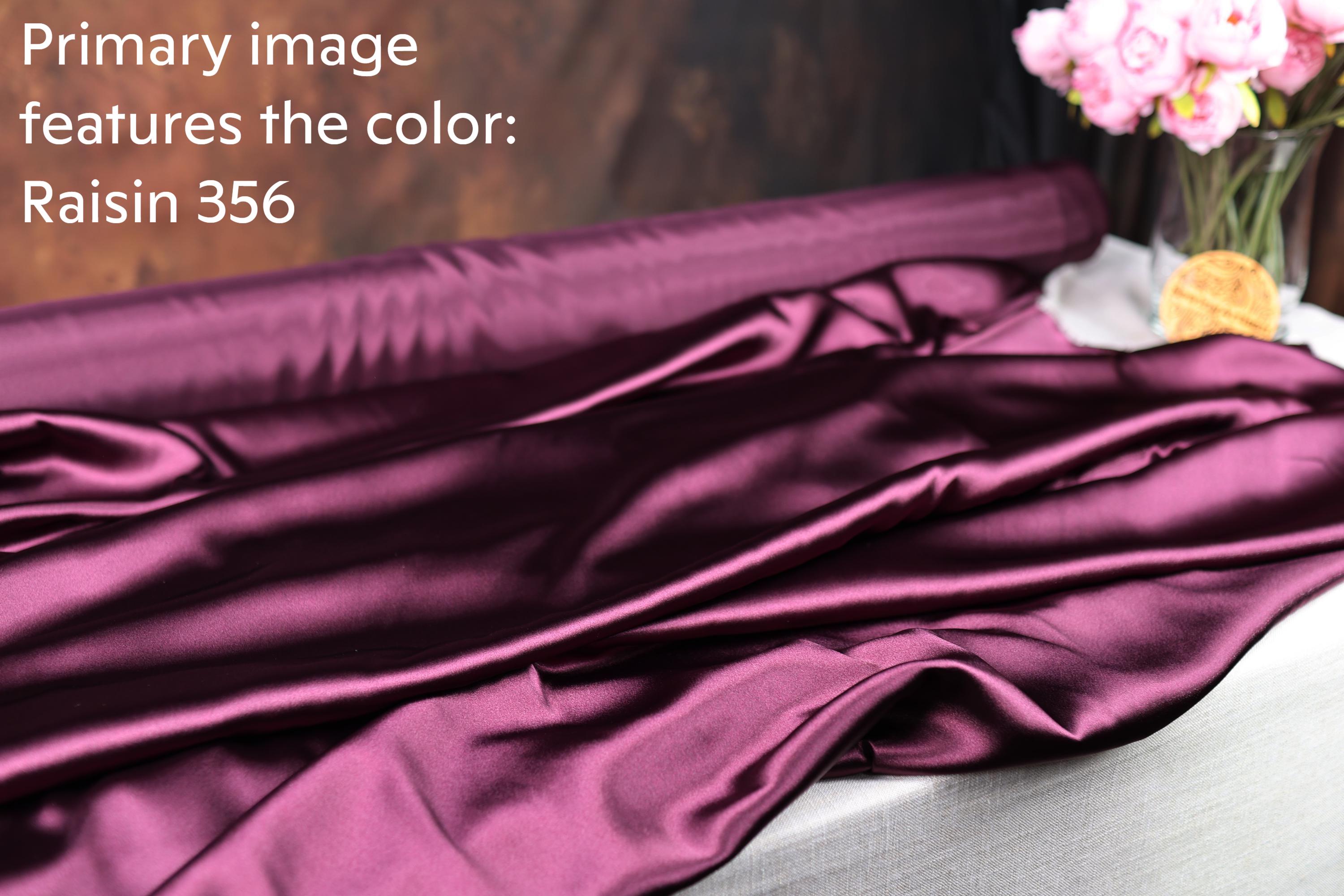 a purple satin fabric, with a vase of pink flowers placed next to it.